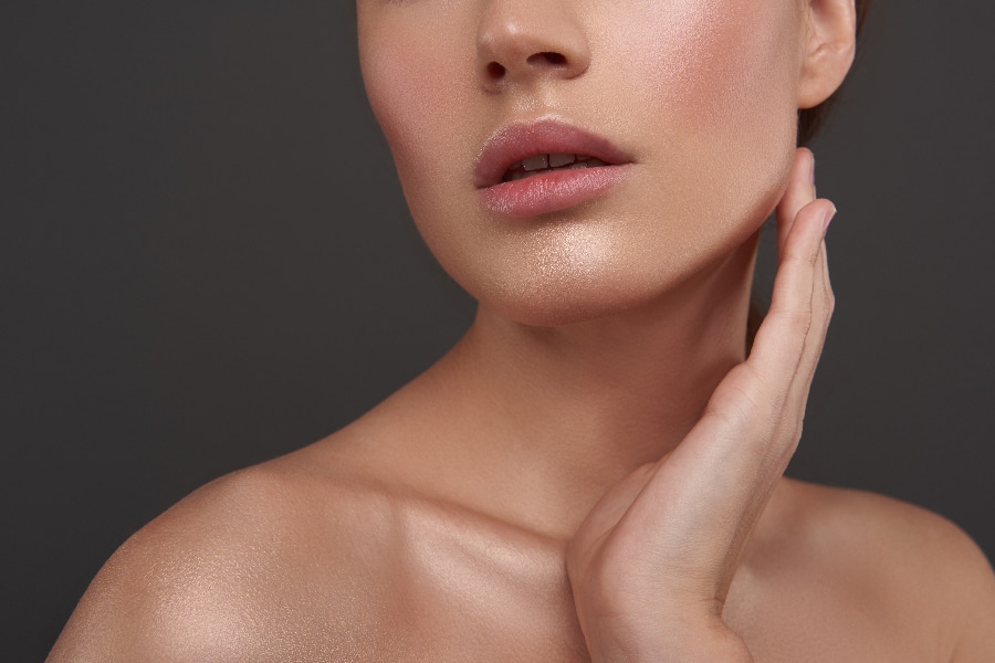 Beautiful young woman with perfect smooth skin touching her face