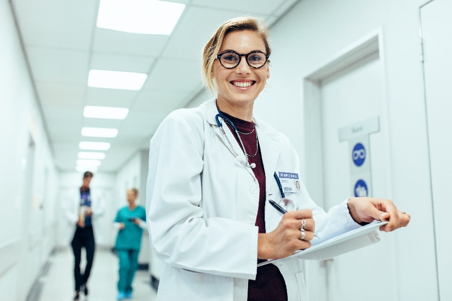 Female physician in hospital corridor writing prescription