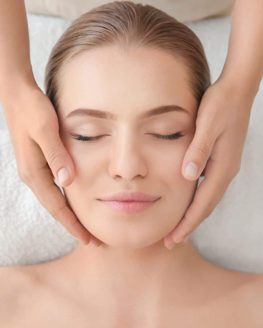 Young woman enjoying of facial massage in spa salon